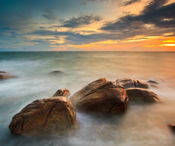 Ηλιοβασίλεμα πέρα από τους βράχους στη θάλασσα — Φωτογραφία Αρχείου