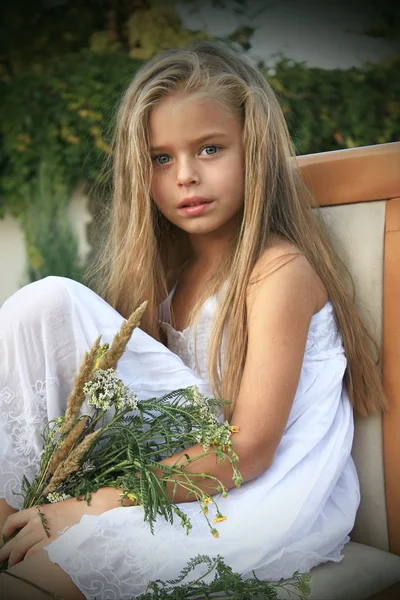 Menina em um vestido branco com flores silvestres — Fotografia de Stock