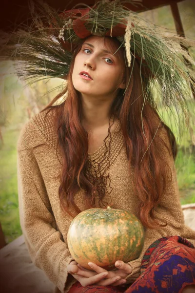 Chica en una corona de otoño con calabaza — Foto de Stock