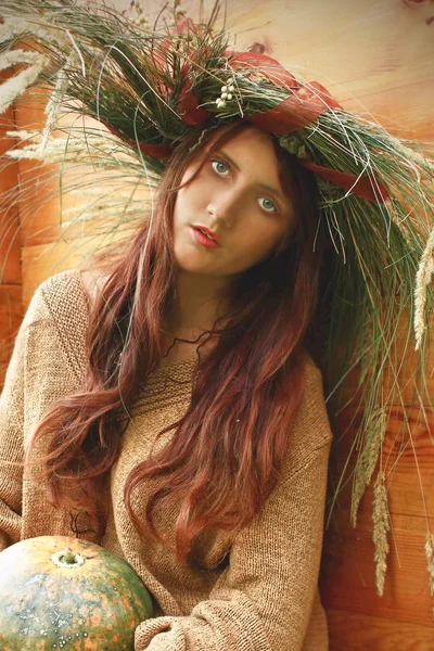 Chica en una corona de otoño con calabaza — Foto de Stock