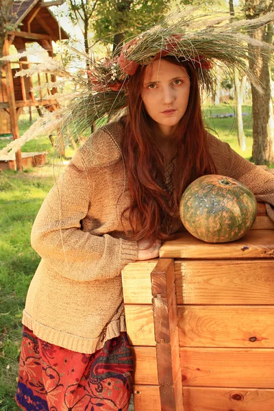 Chica en una corona de otoño con calabaza — Foto de Stock
