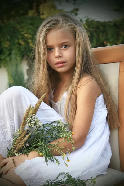 Flicka i en vit klänning med blommor Stockfoto