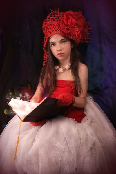 Bir gül karanlık bir arka plan üzerinde kırmızı şapkalı kız — Stok fotoğraf