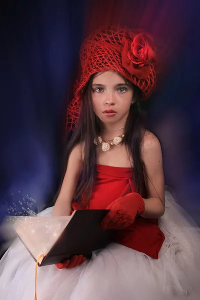 Дівчина в червоному капелюсі з трояндою на темному тлі — стокове фото