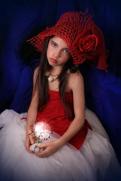 Flicka i en röd mössa med en ros på en mörk bakgrund — Stockfoto