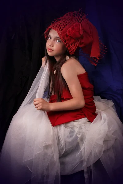 Chica en un sombrero rojo con una rosa sobre un fondo oscuro — Foto de Stock