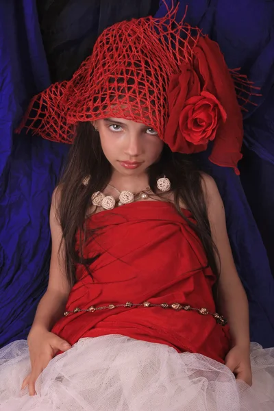 Chica en un sombrero rojo con una rosa sobre un fondo oscuro —  Fotos de Stock