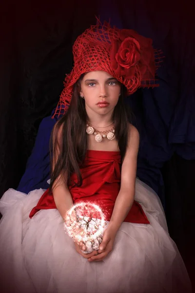 Chica en un sombrero rojo con una rosa sobre un fondo oscuro —  Fotos de Stock