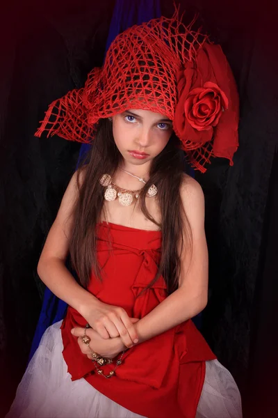 Flicka i en röd mössa med en ros på en mörk bakgrund — Stockfoto