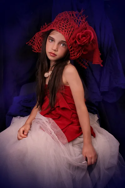 Chica en un sombrero rojo con una rosa sobre un fondo oscuro —  Fotos de Stock