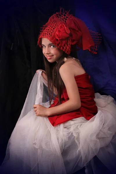Κορίτσι σε ένα κόκκινο καπέλο με ένα τριαντάφυλλο σε σκούρο φόντο Royalty Free Εικόνες Αρχείου