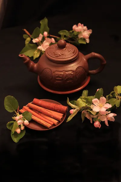 Cinnamon sticks on a black background with a flower cherry — Stock Photo, Image