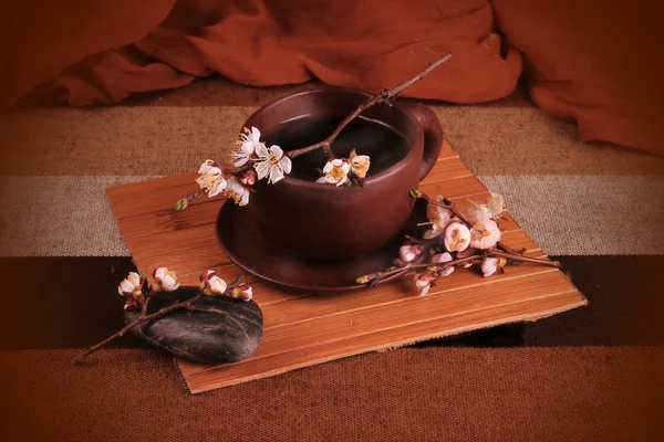 Uma xícara de chá de barro com galho de cereja florescente — Fotografia de Stock