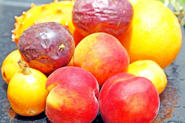 Exotic fruits: orange, kiwano, loquat, peach and passionfruit — Stock Photo, Image
