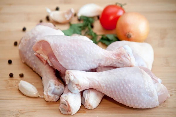 Raw chicken legs with vegetables and spices on the chopping boar