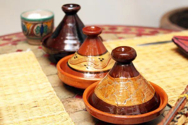 Diferentes tajines de cerâmica com alimentos na mesa — Fotografia de Stock