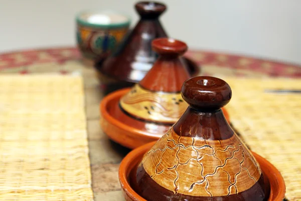 Diferentes tajines de cerâmica com alimentos na mesa — Fotografia de Stock