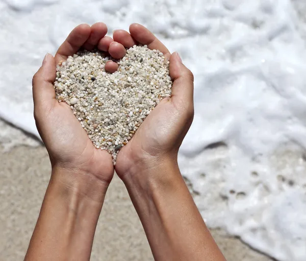 Mellow hart vormgeven van vrouwelijke handen boven strand — Stockfoto