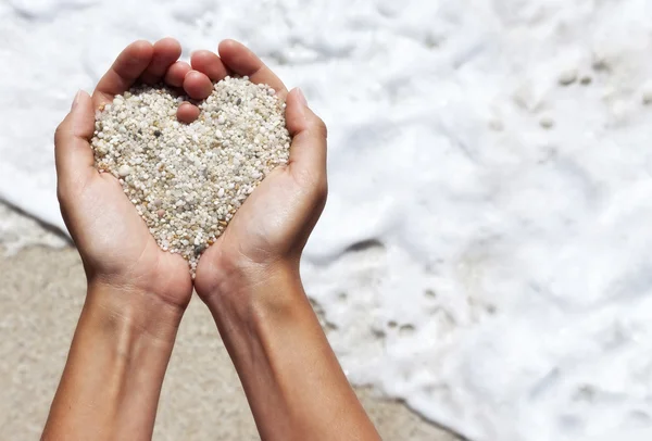 Mellow heart shaping female hands above beach — Stock Photo, Image