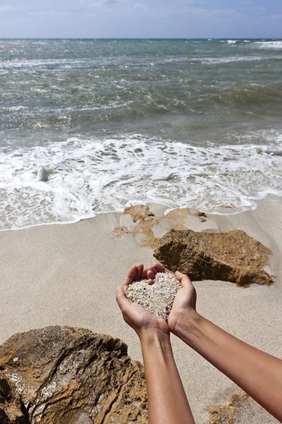 Мягкое сердце формирует женские руки над пляжем — стоковое фото
