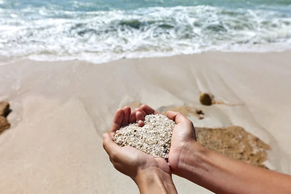 Coeur doux façonnant les mains féminines au-dessus de la plage — Photo