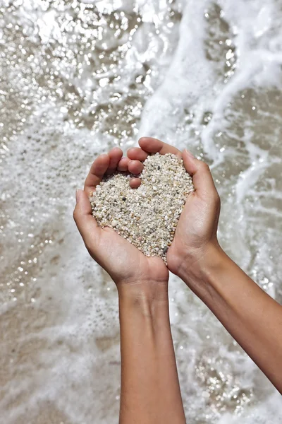 Mellow hart vormgeven van vrouwelijke handen boven strand — Stockfoto