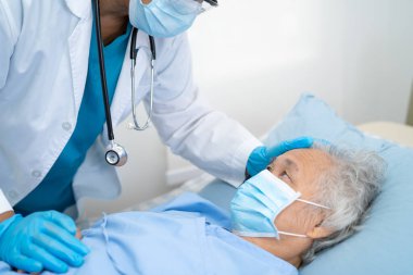 Doktor, güvenlik enfeksiyonunu korumak ve Covid-19 Coronavirus 'u öldürmek için hastanede maske takan yaşlı ve yaşlı bir kadına yardım ediyor..