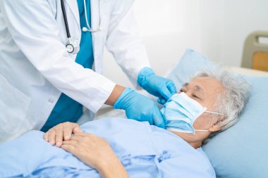 Doktor, güvenlik enfeksiyonunu korumak ve Covid-19 Coronavirus 'u öldürmek için hastanede maske takan yaşlı ve yaşlı bir kadına yardım ediyor..