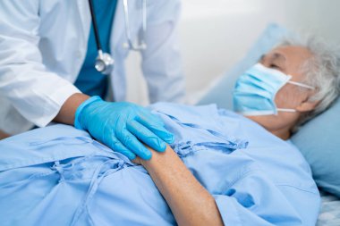 Doktor, güvenlik enfeksiyonunu korumak ve Covid-19 Coronavirus 'u öldürmek için hastanede maske takan yaşlı ve yaşlı bir kadına yardım ediyor..