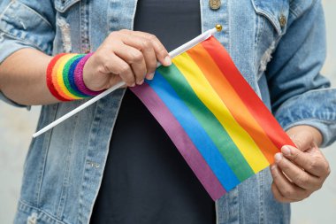 Mavi kot ceket ya da kot pantolon giyen ve elinde gökkuşağı renkli bayrak tutan Asyalı kadın, LGBT gurur ayının sembolü, Haziran sosyal ortamında eşcinsel, lezbiyen, biseksüel, transseksüel, insan hakları.