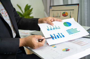 Modern ofis, finans ve iş konseptinde grafik grafik grafiği ve hesap makinesiyle çalışan ve finansal raporları analiz eden Asyalı muhasebeci.