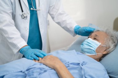 Doktor, hastanede güvenlik enfeksiyonunu korumak ve Covid19 Coronavirus 'u öldürmek için maske takan yaşlı ve yaşlı bir kadına yardım ediyor..