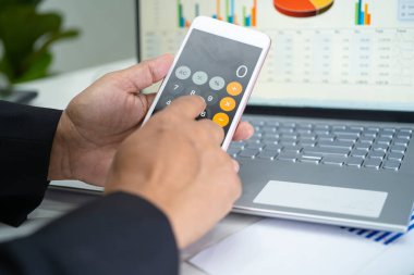 Modern ofis, finans ve iş konseptinde grafik grafik grafiği ve hesap makinesiyle çalışan ve finansal raporları analiz eden Asyalı muhasebeci.