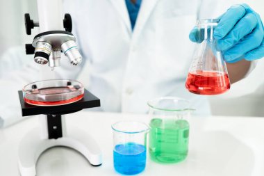 Laboratuvarda mikroskopla çalışan Asyalı biyokimyacı ya da mikrobiyolog. Coronavirus salgınını korumak için. Covid19, bakteri ve mikroplar..