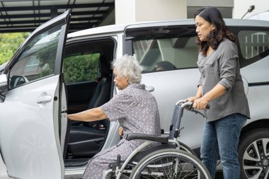 Asyalı yaşlı ve yaşlı kadın hastaların arabasına binmelerine yardım edin ve destek olun..