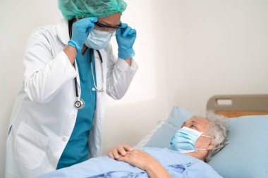 Doktor, güvenlik enfeksiyonunu korumak ve Covid-19 Coronavirus 'u öldürmek için hastanede maske takan yaşlı ve yaşlı bir kadına yardım ediyor..