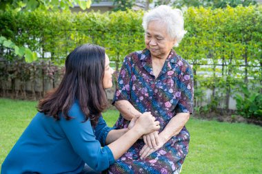 Bakıcısı olan Asyalı yaşlı kadın doğa parkında eğleniyor ve mutlu..