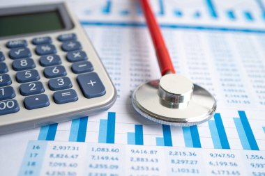 Tablolar ve grafikler, kağıt, Finans, Hesap, İstatistik, Yatırım, Analitik araştırma veri ekonomisi ve İş dünyası konsepti üzerindeki steteskop ve hesap makinesi.