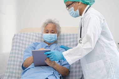 Doktor, güvenlik enfeksiyonunu korumak ve Covid-19 Coronavirus 'u öldürmek için hastanede maske takan yaşlı ve yaşlı bir kadına yardım ediyor..