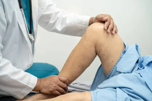 アジアの医師理学療法士が整形外科診療所看護師病院における高齢者の膝と脚の検査 マッサージ 治療を担当 — ストック写真