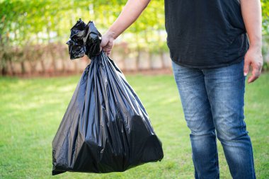 Kaldırımda siyah plastik çöp torbaları taşıyan bir kadın. Temiz çevre kavramı..