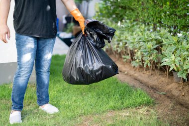 Kaldırımda siyah plastik çöp torbaları taşıyan bir kadın. Temiz çevre kavramı..