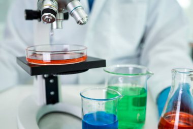 Laboratuvarda mikroskopla çalışan Asyalı biyokimyacı ya da mikrobiyolog. Coronavirus salgınını korumak için. Covid19, bakteri ve mikroplar..