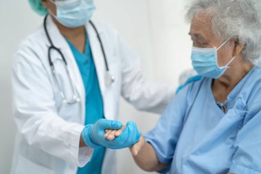 Doktor, güvenlik enfeksiyonunu korumak ve Covid 19 Coronavirus 'u öldürmek için hastanede maske takan yaşlı ve yaşlı bir kadına yardım ediyor..