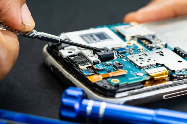 Teknisyen, cep telefonunun içinde lehim kullanarak tamir ediyor. Bütünleşik devre. veri kavramı, donanım, teknoloji.