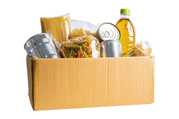 Продукты для пожертвования, хранения и доставки. Различные продукты питания, макароны, растительное масло и консервы в картонной коробке.