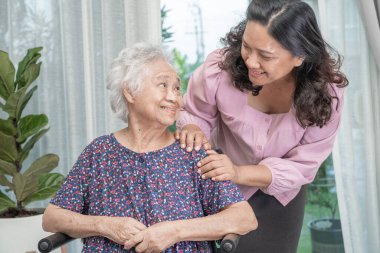 Tekerlekli sandalyede oturan ve güvenlik enfeksiyonu Covid 19 Coronavirus 'u korumak için maske takan yaşlı yaşlı kadına yardım edin..