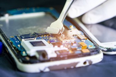 Teknisyen, cep telefonunun içinde lehim kullanarak tamir ediyor. Bütünleşik devre. veri kavramı, donanım, teknoloji.