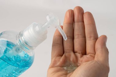 Yeni, normal, Asyalı çalışan kadın emniyet enfeksiyonunu korumak ve Covid-19 Coronavirus 'u ofisinde öldürmek için mavi alkol dezenfektanı ile elini yıkıyor..