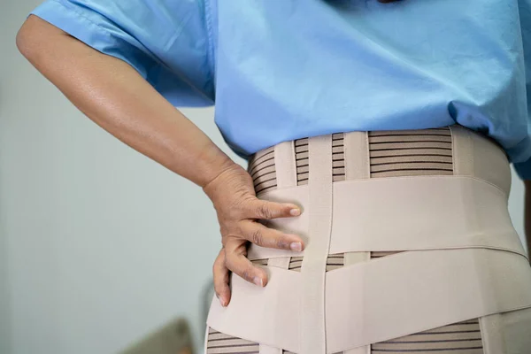 Asian lady patient wearing back pain support belt for orthopedic lumbar with walker.